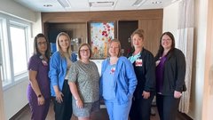 group of lactation consultants standing in patient room smiling for photo