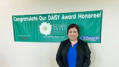 nurse-veronica-jones-standing-in-front-of-daisy award banner